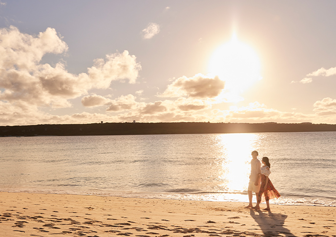 夕方のビーチを歩くカップル