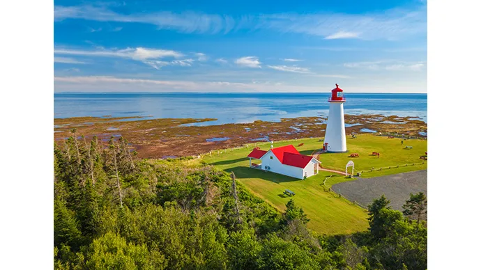 ©Tourism PEI / Sander Meurs　穏やかな海を背景に白壁と赤が際立つ灯台を捉えたショット