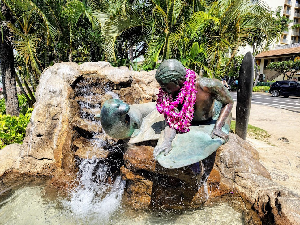 サーフィンを楽しむ少年とハワイアン・モンクシールの像